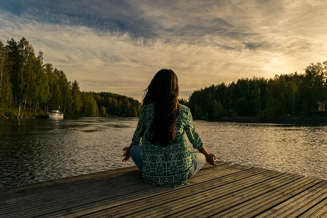 Mujer, de espaldas, haciendo mindfulness en un lago.